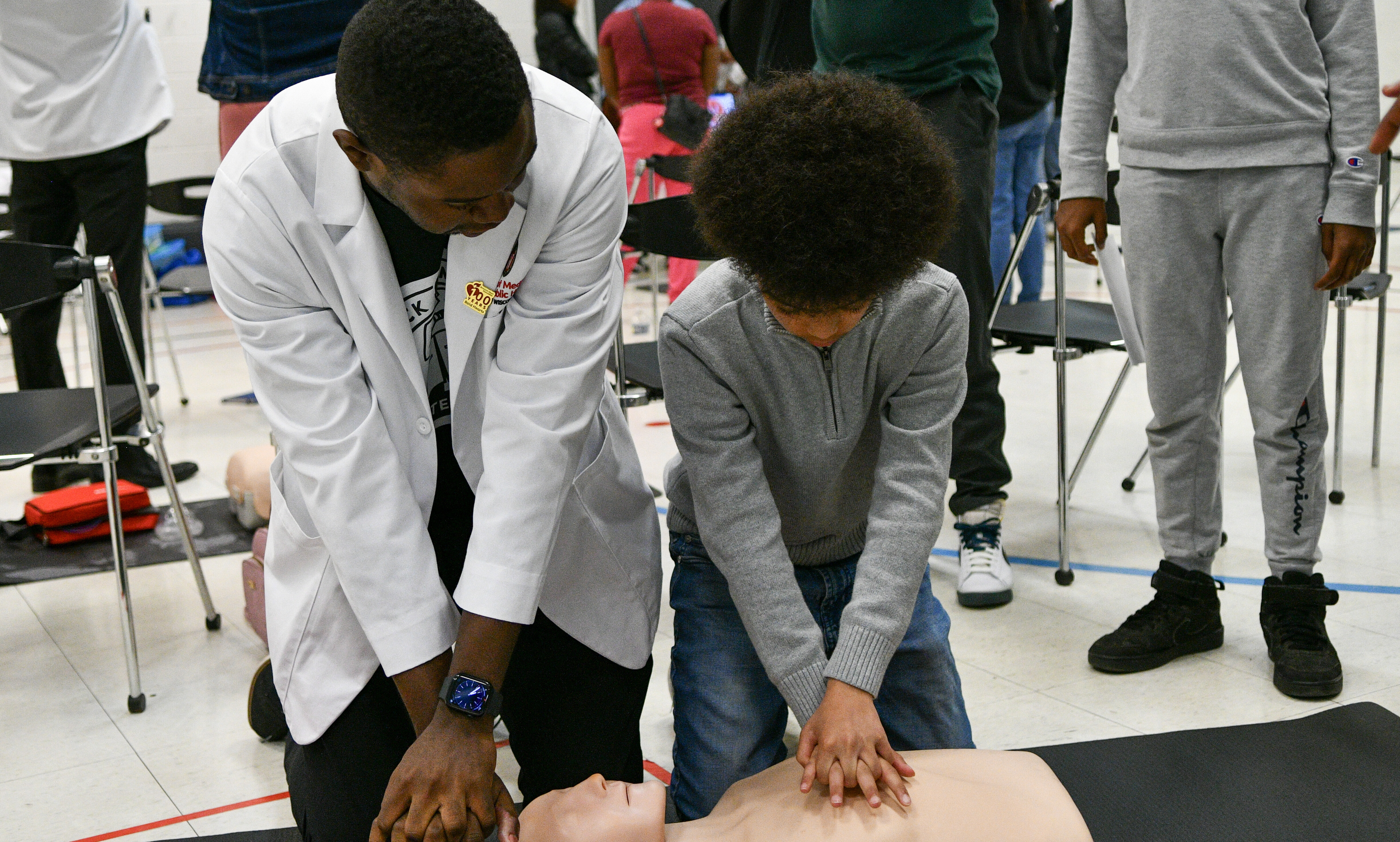 A medical professional demonstrates chest compressions for a student.