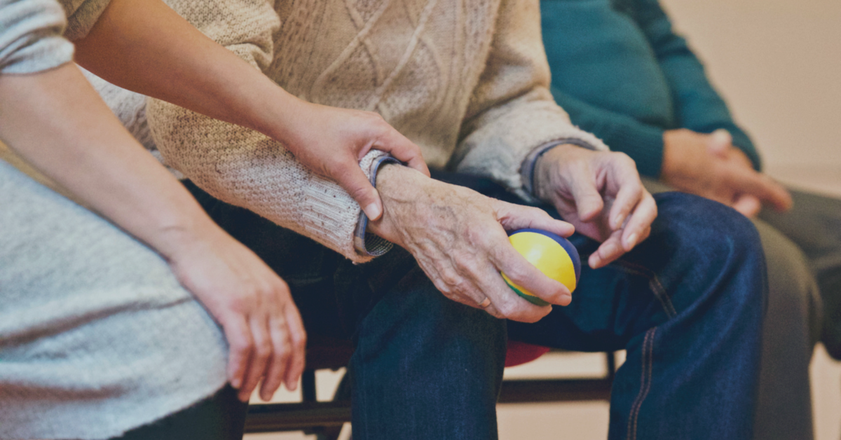 Hands of elderly adults hold a small ball.
