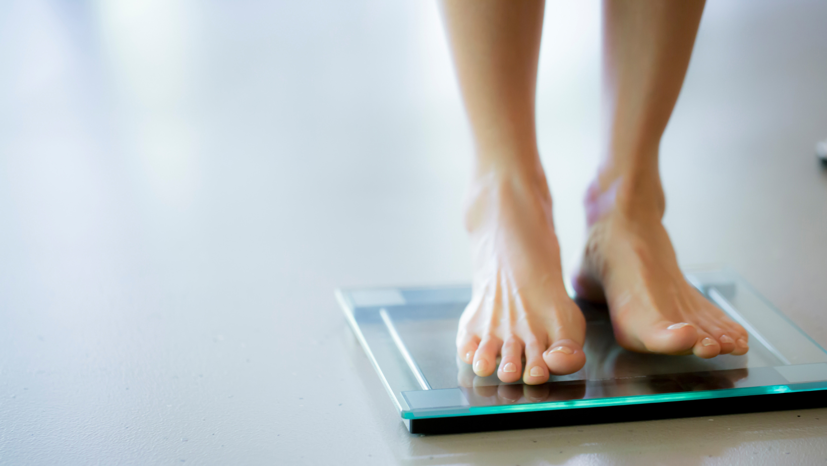 Two feet stand on a scale. AHW explores the question, "are fad diets healthy" in this article.