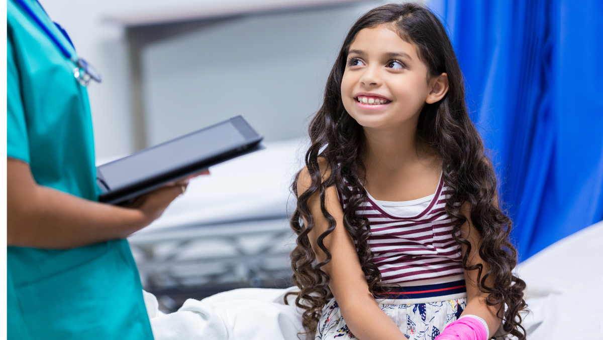 A girl smiles at her doctor in an emergency department.