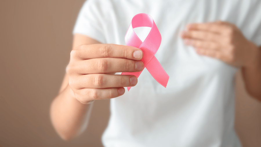 A person holds a pink ribbon representing breast cancer awareness. Learn how AHW health research grants support breast cancer advancements.