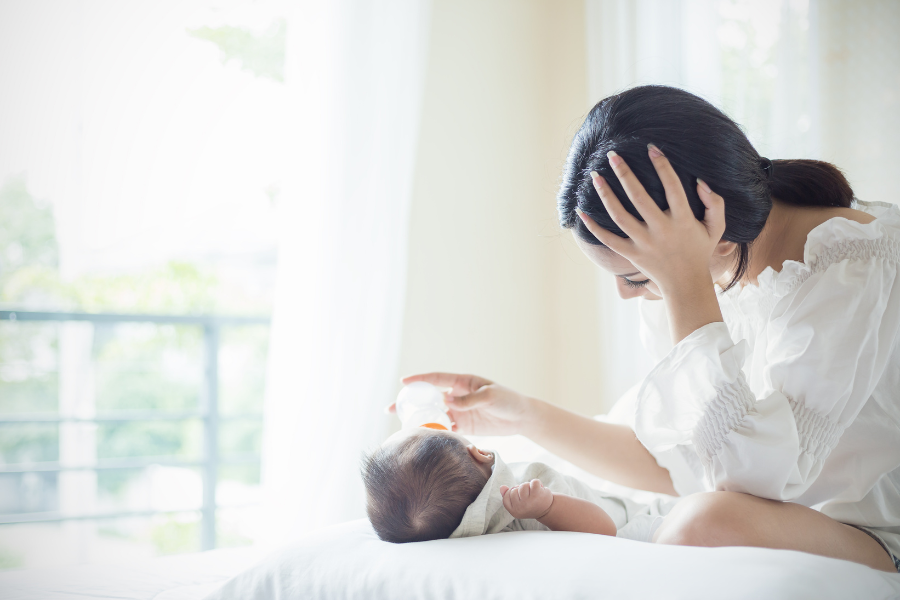 A mother feeds her baby a bottle. With community health grants in Wisconsin, AHW has supported Maternal Mental Health concerns.