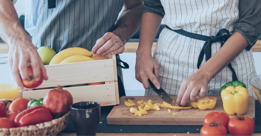 Two people prepare a healthy meal on a countertop.